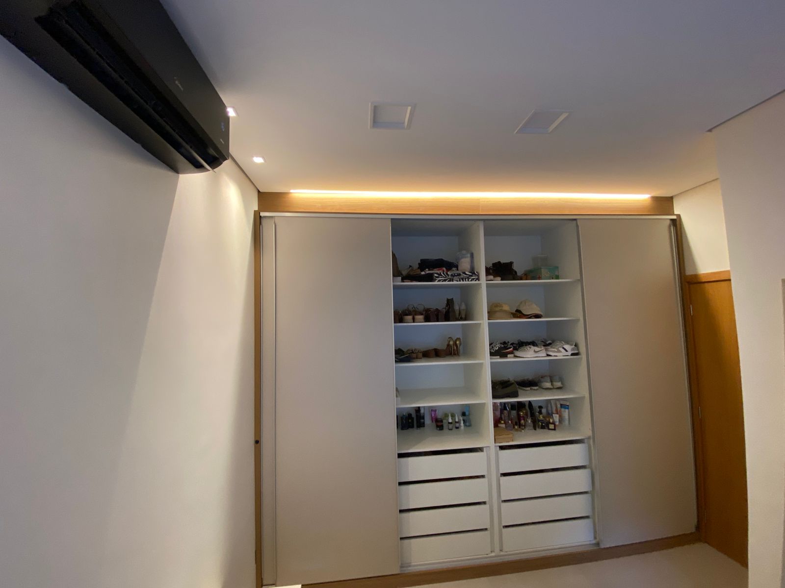 Guarda-roupa planejado com portas de correr abertas, exibindo nichos, gavetas e organização interna