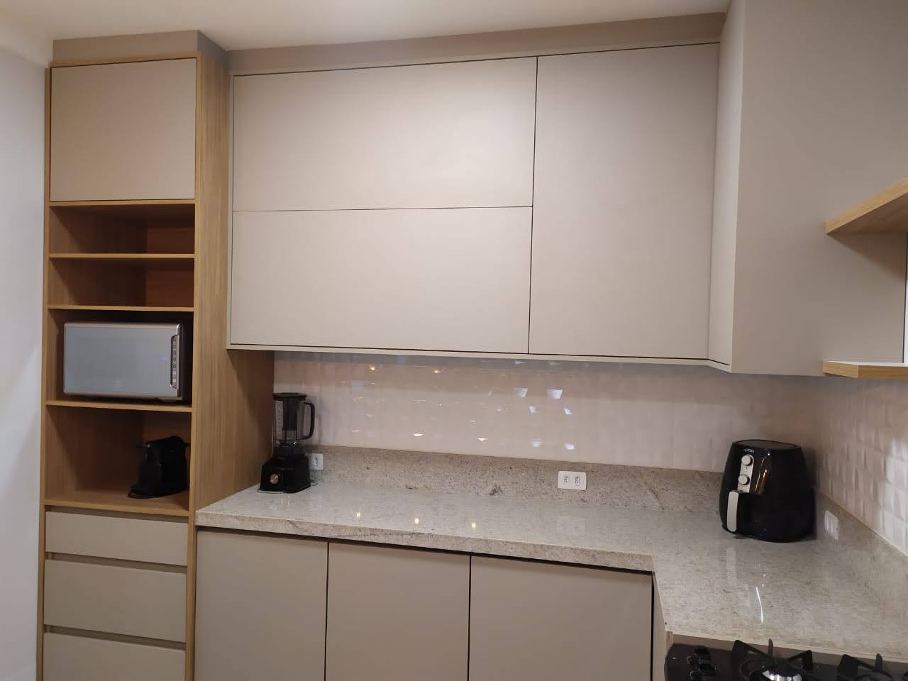 Cozinha planejada com armários superiores em tom neutro, nichos abertos e cooktop embutido