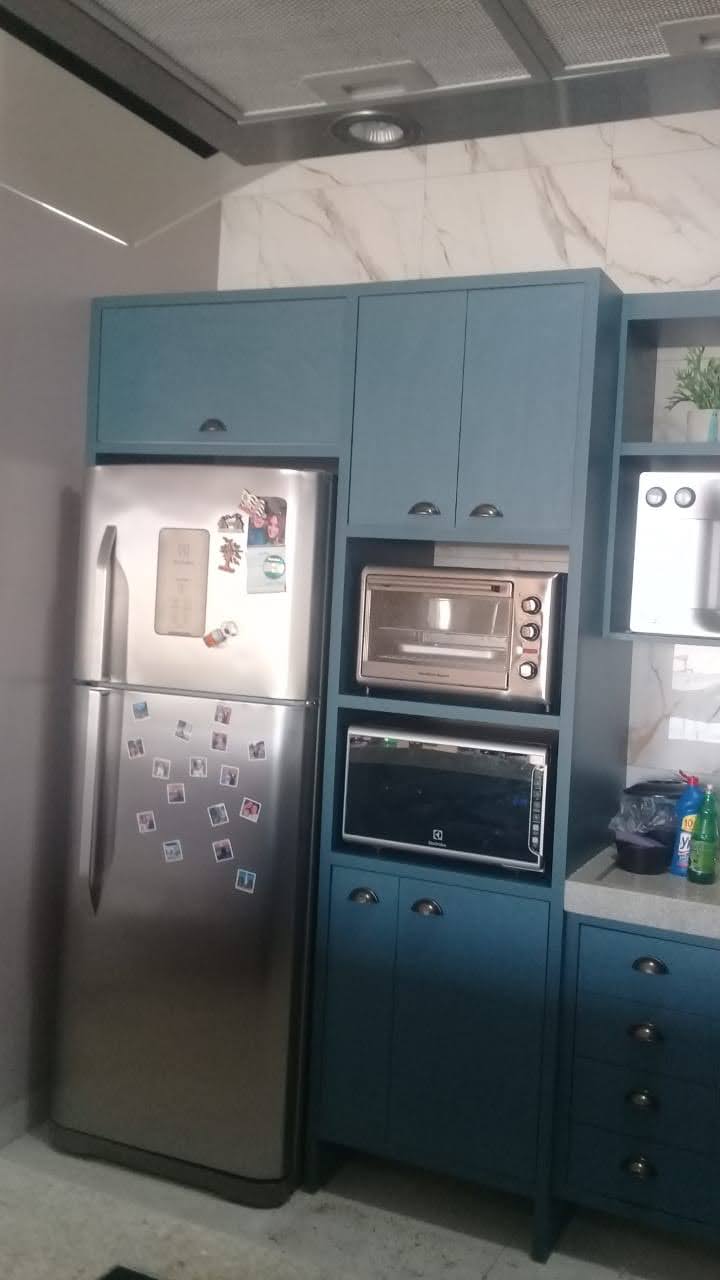 Módulo planejado azul ao lado da geladeira com nichos e espaço para eletrodomésticos